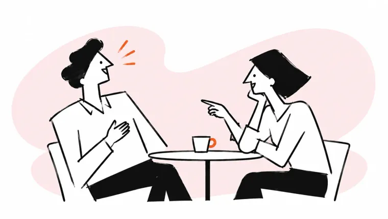 Two colleagues share a laugh over a cup at a small table.